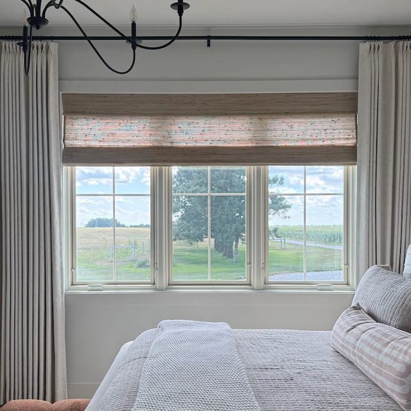 Custom curtains and woven wood shade in a bedroom